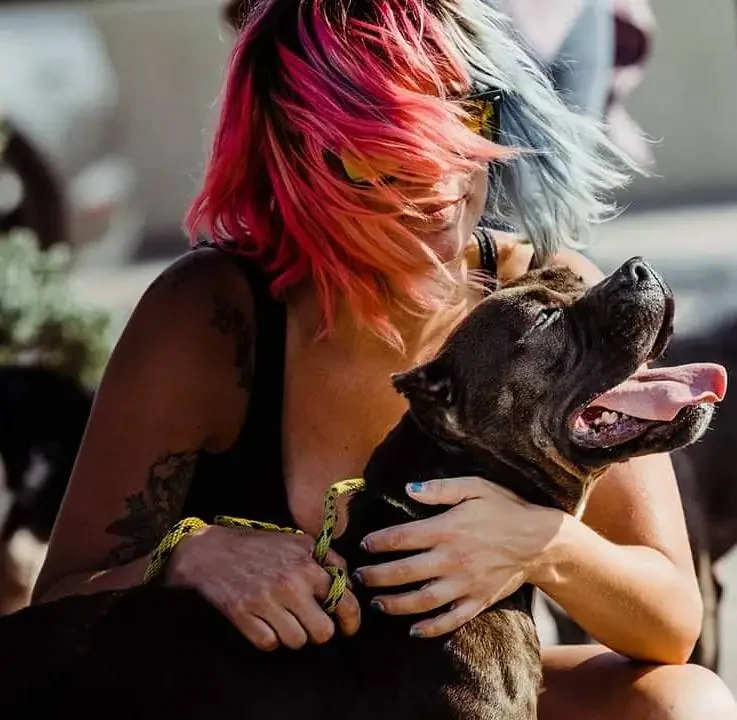 Marilyn embracing a rescue pit bull in a moment of quiet trust, golden-hour light